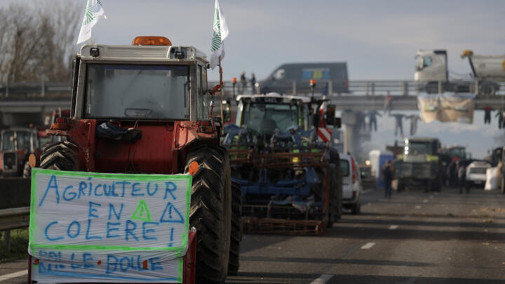 This photograph taken on January 22, 2024 shows a tractor with a banner that reads "angry farmer" as farmers continue a blockade of the A64 highway in protest against taxation and declining income, ne